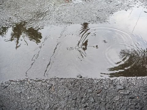 The afternoon sky was reflected in a puddle of water on the sidewalk. shot wi Stock Photos