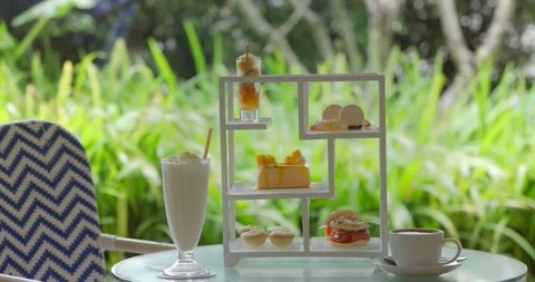 Afternoon tea set with cake, macarons, and milkshake on outdoor patio Stock Footage 312000349