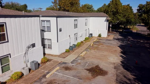 Afternoon view of a multifamily housing complex with an empty parking lot, air Stock Footage 340926170