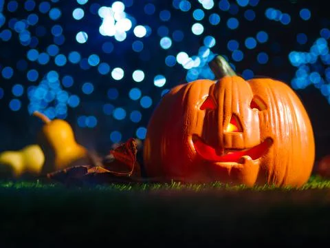 Against the backdrop of a blue starry sky Halloween pumpkin with a sinister s Stock Photos