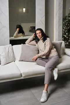 Against the backdrop of a high-end interior, a brunette in a beige sweater and Stock Photos