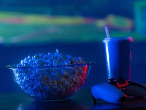 Against the backdrop of a large TV screen with a sports game - popcorn in a b Stock Photos