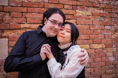 Against the backdrop of a red brick wall, young couple holds each other tig.. 库存照片