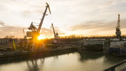 Against the backdrop of the rising sun, cranes work at the shipyard. Video stock 86411180