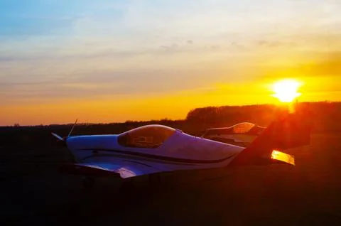 Against the backdrop of the setting sun we see the silhouettes of airplanes Stock Photos
