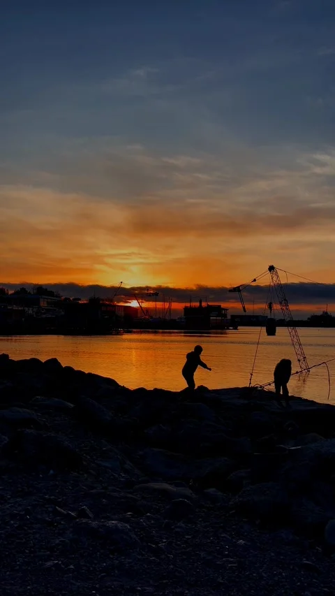 Against the background of sunset, boys walk on stones by the sea Stock Footage 296987958
