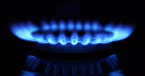 Against a dark background, in slow motion, a  gas cooking hob burner ignites. Stock Footage 266815137