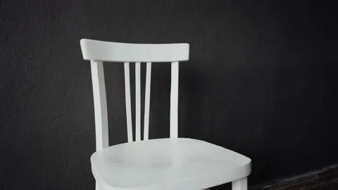 Against the grey wall stands an old white chair. Close-up. Stock Footage 135311635