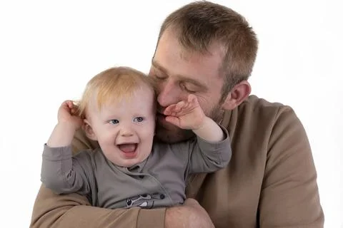 Against a white background, dad gently kisses his one-year-old son. Father an Stock Photos