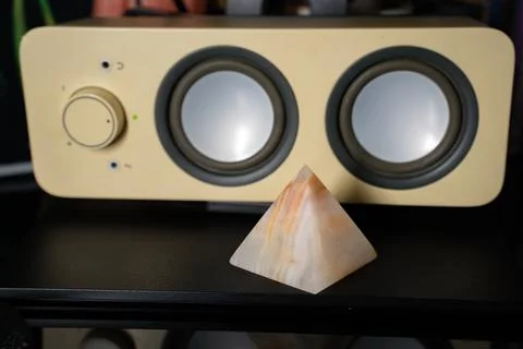 Agate pyramid on table in front of white speaker Stock Photos