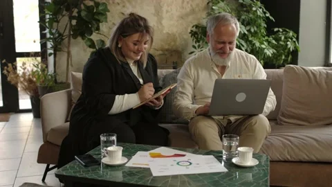 Age diverse colleagues sit on couch in creative office discussing proactive idea Stock Footage 166060945