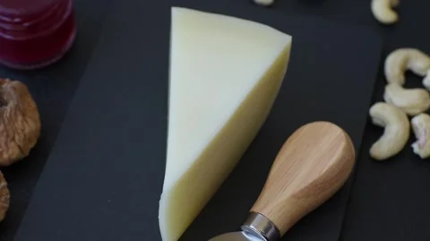 Aged cheese in a triangular block with jam, figs, and nuts. Aged cheese Stock Footage 336245018