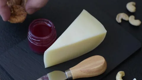 Aged cheese in a triangular block with jam, figs, and nuts. Aged cheese Stock Footage 336245019