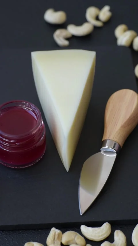 Aged cheese in a triangular block with jam, figs, and nuts. Aged cheese Stock Footage 336245023