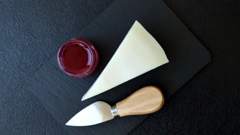 Aged cheese in a triangular block with jam, figs, and nuts. Aged cheese Stock Footage 336245045