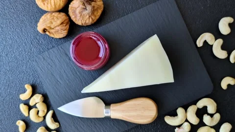 Aged cheese in a triangular block with jam, figs, and nuts. Aged cheese Stock Footage 336245050