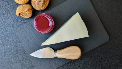 Aged cheese in a triangular block with jam, figs, and nuts. Aged cheese Stock Footage 336245052