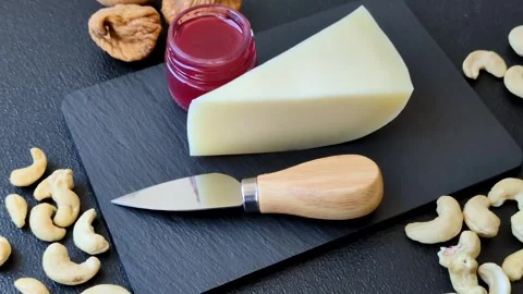 Aged cheese in a triangular block with jam, figs, and nuts. Aged cheese Stock Footage 336245054