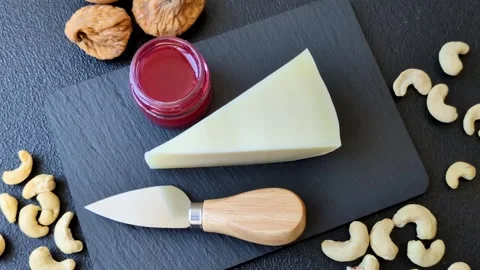 Aged cheese in a triangular block with jam, figs, and nuts. Aged cheese Stock Footage 336245055