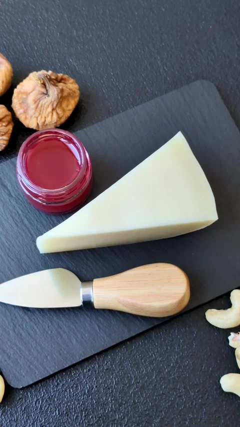 Aged cheese in a triangular block with jam, figs, and nuts. Aged cheese Stock Footage 336245057