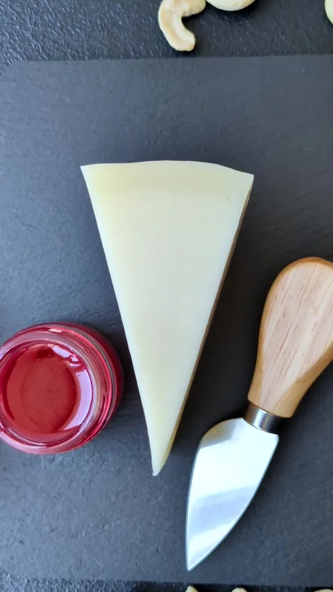 Aged cheese in a triangular block with jam, figs, and nuts. Aged cheese Stock Footage 336245058