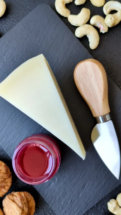 Aged cheese in a triangular block with jam, figs, and nuts. Aged cheese Stock Footage 336245064