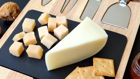 Aged cheese in a triangular block with jam, figs, and nuts. Aged cheese Stock Footage 336245082
