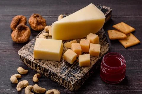 Aged cheese in a triangular block with jam, figs, and nuts. Aged cheese Stock Photos