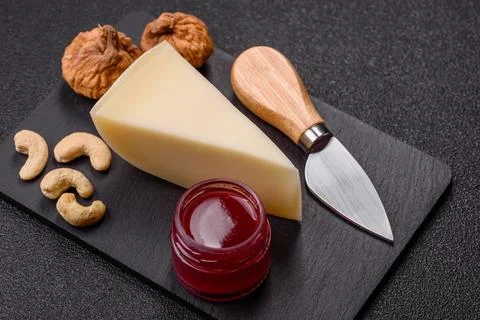 Aged cheese in a triangular block with jam, figs, and nuts. Aged cheese Stock Photos