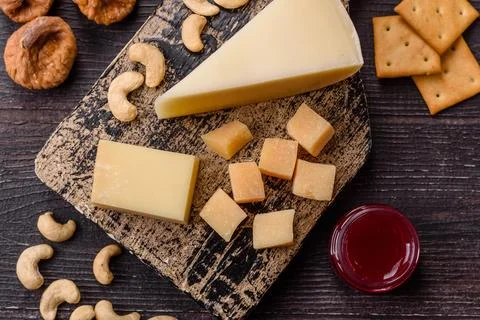 Aged cheese in a triangular block with jam, figs, and nuts. Aged cheese Stock Photos