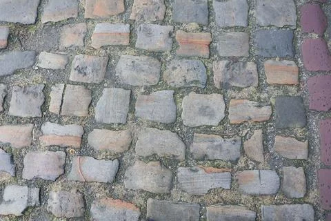 An aged cobblestone path, overgrown with grass, creating a rustic vintage Stock-Fotos