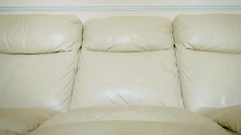 Aged cream leather sofa with soft cushions and visible signs of everyday wear Stock Footage 345715026