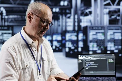 Aged engineer coding in data center Stock Photos