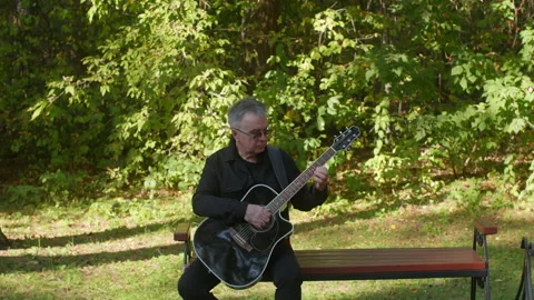 An aged gentleman softly performs harmonious melodies on his stringed instrument Stock Footage 331664809