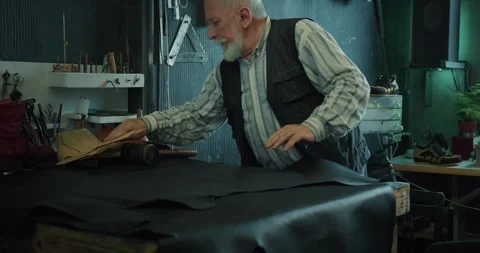 Aged good-looking shoemaker preparing his workplace for new workday. Video stock 246306781
