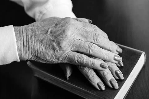 Aged hands placed on a book. Stock Photos