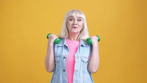 Aged lady practice use small barbells isolated vivid color background Stock Footage 189843075