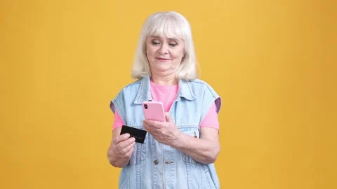 Aged lady using gadget pay bank card buyings isolated shine color background Stock Footage 189842551