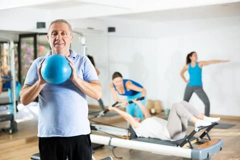 Aged man doing chest muscles exercises with pilates ball Stock Photos