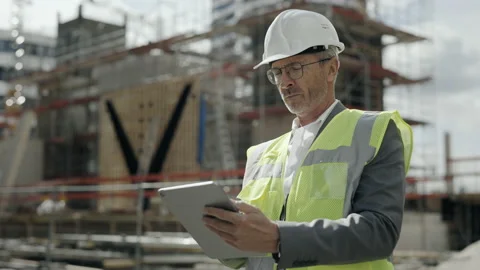 Aged man in helmet working on tablet on construction site Video stock 167226351