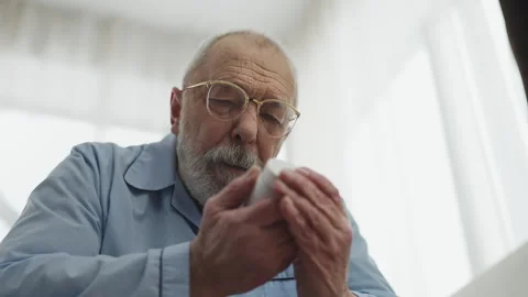 Aged man putting on glasses and reading pill bottle label, checking prescription Stock Footage 346484922
