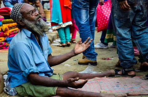 An aged man with specs begging on the street due to having paraplegia, paralysis Foto stock