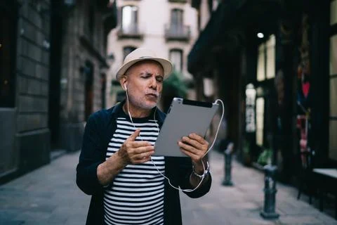Aged man in straw hat using app on digital tablet for networking Stock Photos
