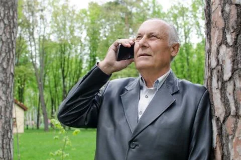 Aged man is using cellphone in the park Stock Photos