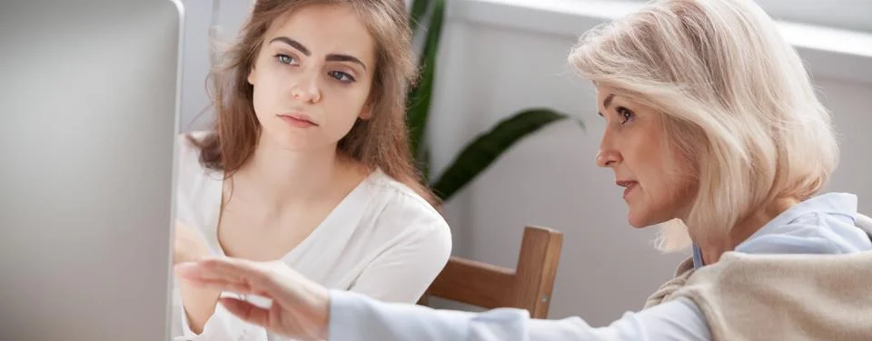 Aged mentor showing on computer screen helping intern understand program Stock-Fotos