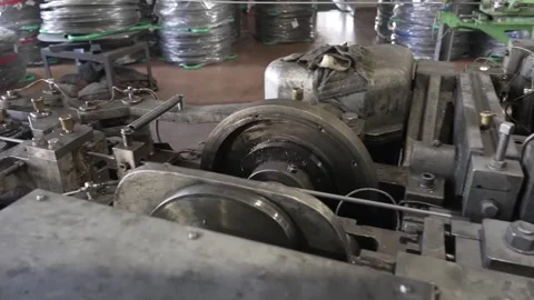 Aged metal forming machine shapes chain links surrounded by coiled wire in an Stock Footage 339123151