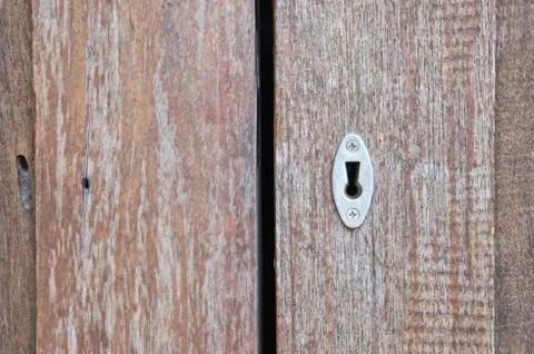 Aged old key hole on opened wooden door Stock Photos