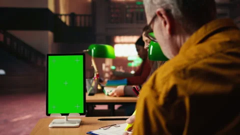 Aged old man using isolated mockup screen on tablet at a public library Stock Footage 313303444