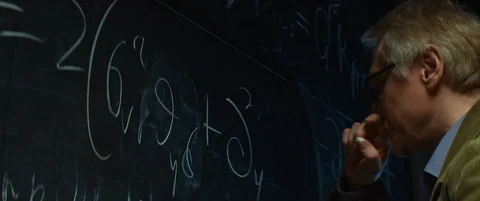 Aged Professor or scientist working, writes equations with chalk on chalkboard Stock Footage 123277648