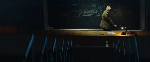 Aged professor working on formula or equation late at night at University Stock Footage 123186414
